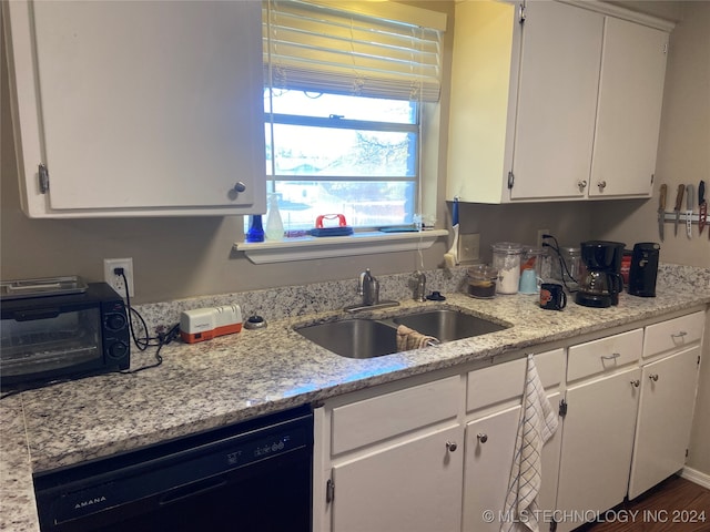 kitchen with light stone counters, dark hardwood / wood-style floors, sink, white cabinets, and dishwasher