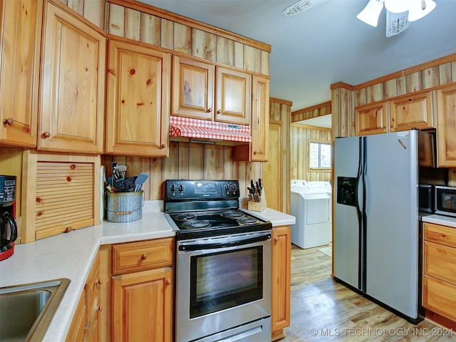 kitchen with washer and clothes dryer, wooden walls, light hardwood / wood-style flooring, ceiling fan, and appliances with stainless steel finishes