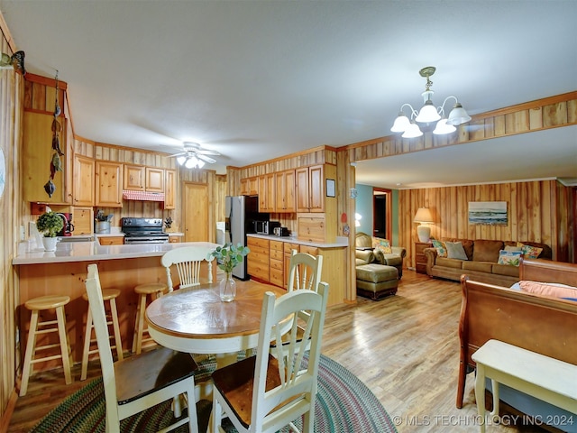 dining room with ceiling fan with notable chandelier, light wood-type flooring, and sink