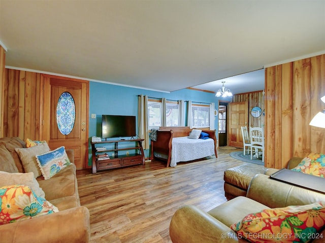 living room with wooden walls, an inviting chandelier, hardwood / wood-style flooring, and ornamental molding