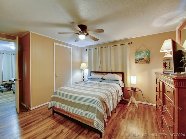 bedroom with ceiling fan, a textured ceiling, and light wood-type flooring