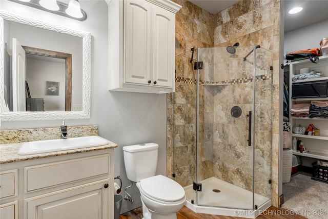 bathroom featuring walk in shower, vanity, toilet, and hardwood / wood-style flooring