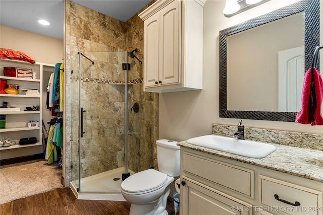 bathroom with hardwood / wood-style floors, a shower with door, vanity, and toilet