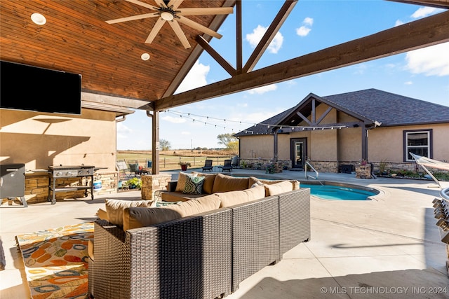 view of pool featuring an outdoor kitchen, ceiling fan, an outdoor hangout area, and a patio area