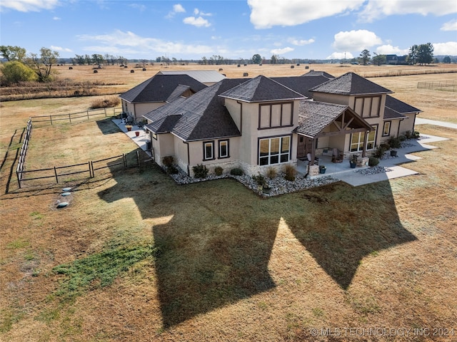 rear view of property with a lawn, a rural view, and a patio area