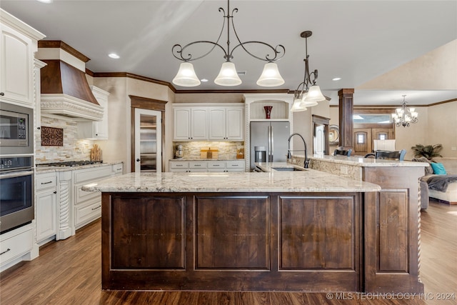 kitchen with pendant lighting, hardwood / wood-style floors, appliances with stainless steel finishes, and a spacious island