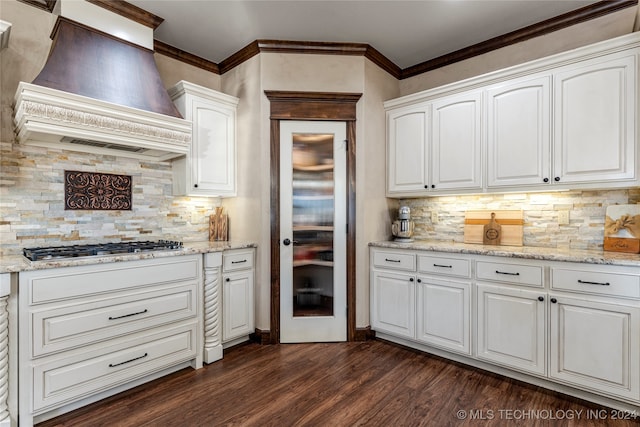 kitchen with tasteful backsplash, dark hardwood / wood-style floors, light stone countertops, white cabinets, and custom exhaust hood