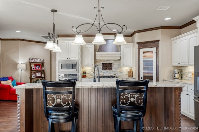 kitchen featuring pendant lighting, light stone counters, and white cabinets