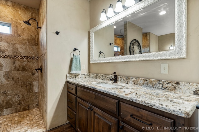 bathroom with vanity, a tile shower, and wood-type flooring