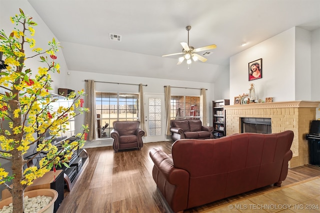 living room with hardwood / wood-style flooring, ceiling fan, lofted ceiling, and a brick fireplace