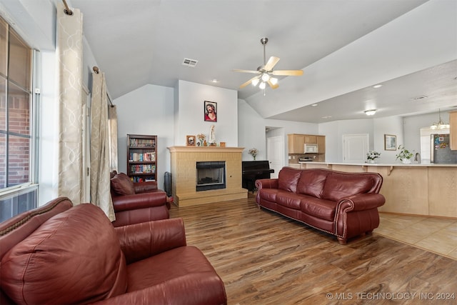 living room featuring ceiling fan, lofted ceiling, a fireplace, and light hardwood / wood-style flooring