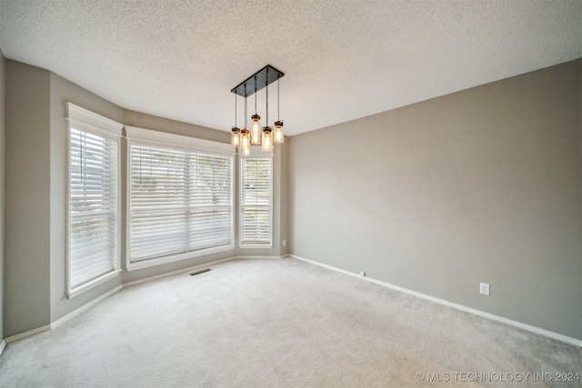 carpeted empty room featuring a textured ceiling