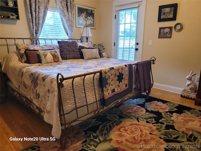 bedroom with multiple windows and hardwood / wood-style flooring