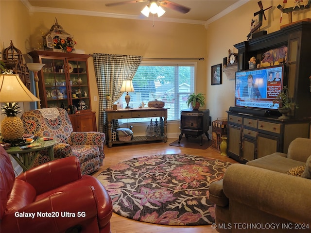 living room featuring a wood stove, light hardwood / wood-style floors, ceiling fan, and crown molding