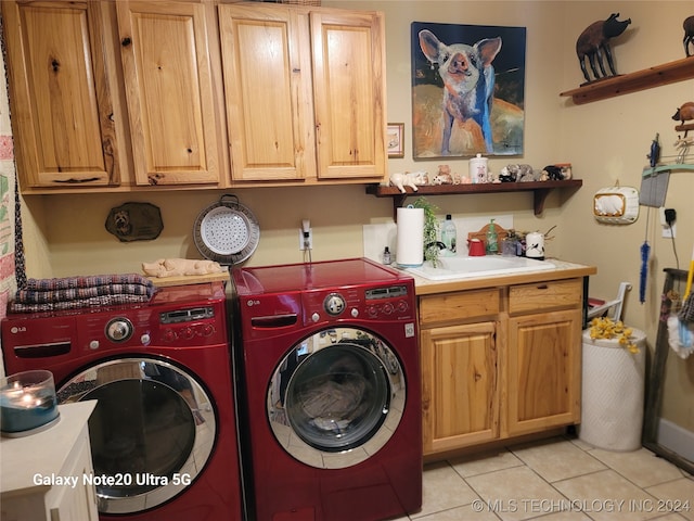 clothes washing area with sink, cabinets, washing machine and clothes dryer, and light tile patterned floors