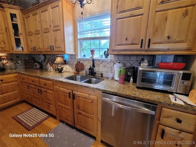 kitchen with sink, stone counters, light hardwood / wood-style flooring, dishwasher, and decorative backsplash