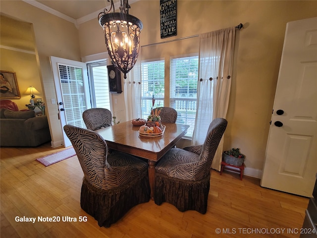 dining room with light hardwood / wood-style floors, a chandelier, and crown molding