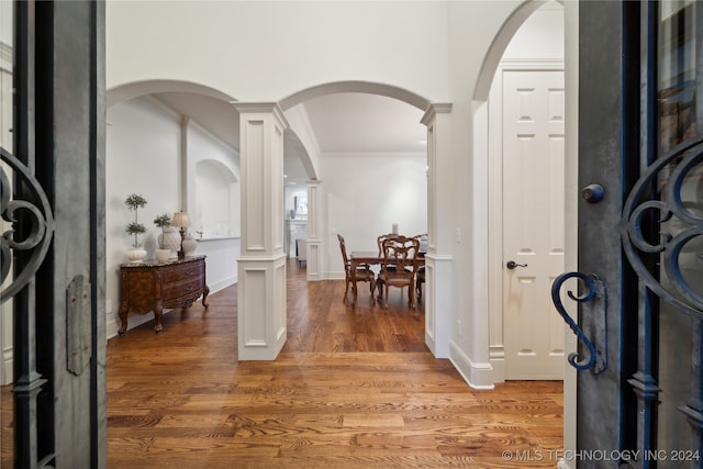 entryway with ornate columns, hardwood / wood-style flooring, and crown molding