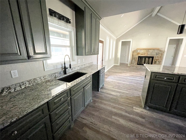 kitchen featuring lofted ceiling with beams, light stone counters, a fireplace, dark hardwood / wood-style floors, and sink