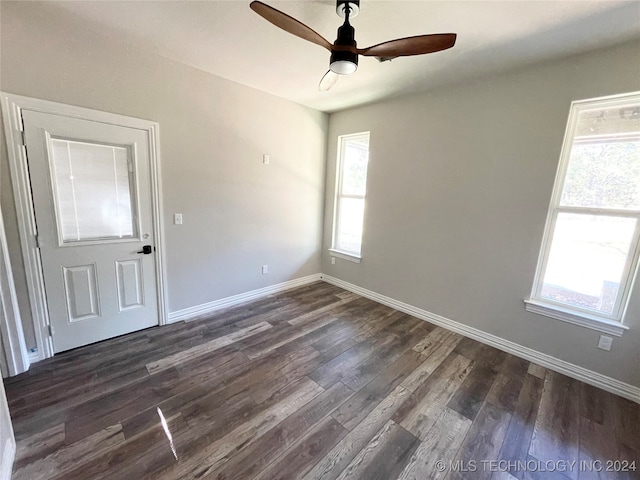 empty room with dark hardwood / wood-style flooring, ceiling fan, and plenty of natural light