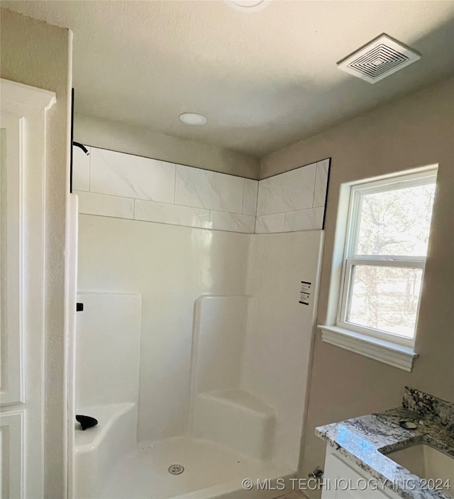 bathroom with a shower, vanity, and a textured ceiling