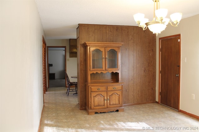 dining room featuring wooden walls and a notable chandelier