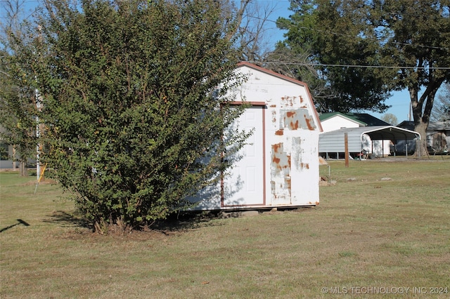 view of outbuilding featuring a lawn and a carport