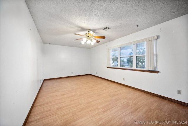 spare room with ceiling fan, a textured ceiling, and light wood-type flooring