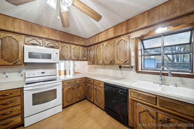 kitchen with a textured ceiling, sink, white appliances, ceiling fan, and light hardwood / wood-style flooring