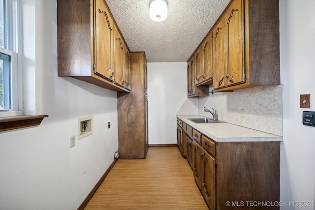 kitchen featuring a textured ceiling, light hardwood / wood-style flooring, sink, and tasteful backsplash