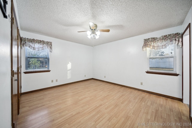 empty room with wood-type flooring, ceiling fan, and a textured ceiling