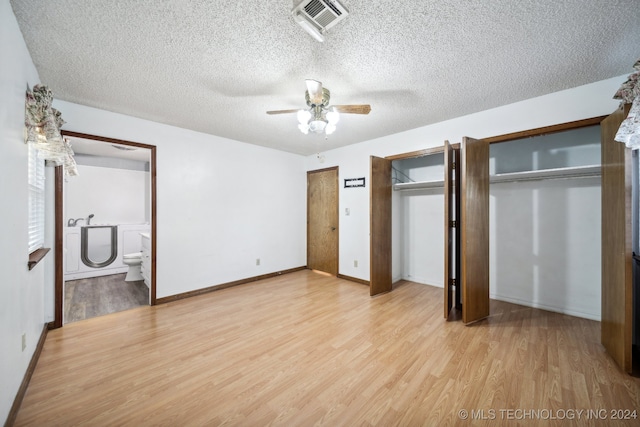 unfurnished bedroom with ceiling fan, a textured ceiling, multiple closets, connected bathroom, and light wood-type flooring