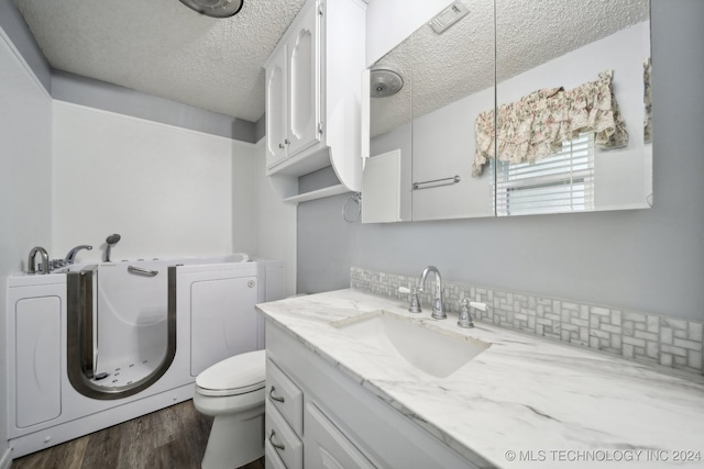 bathroom featuring hardwood / wood-style floors, vanity, a textured ceiling, and decorative backsplash