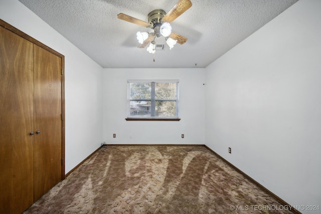 unfurnished bedroom featuring ceiling fan, a textured ceiling, a closet, and carpet floors