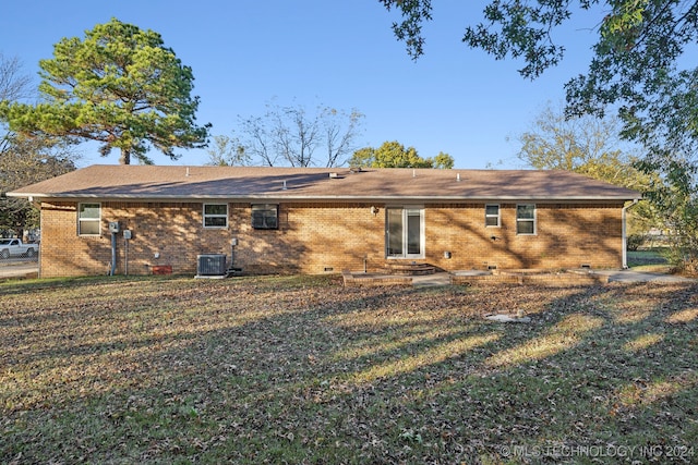 rear view of property with central air condition unit and a lawn