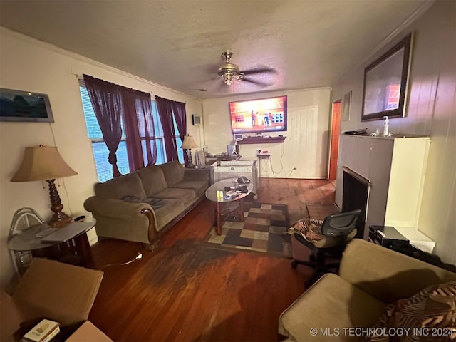 living room featuring a textured ceiling, dark wood-type flooring, and ceiling fan