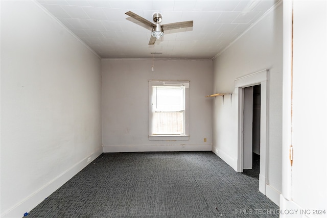 empty room with ceiling fan, dark carpet, and ornamental molding