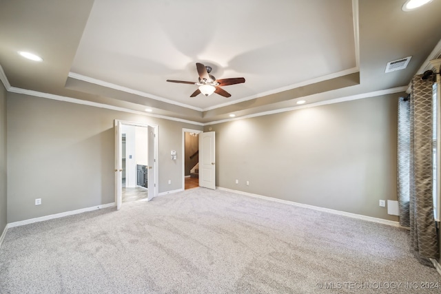 empty room featuring ornamental molding, carpet floors, ceiling fan, and a tray ceiling