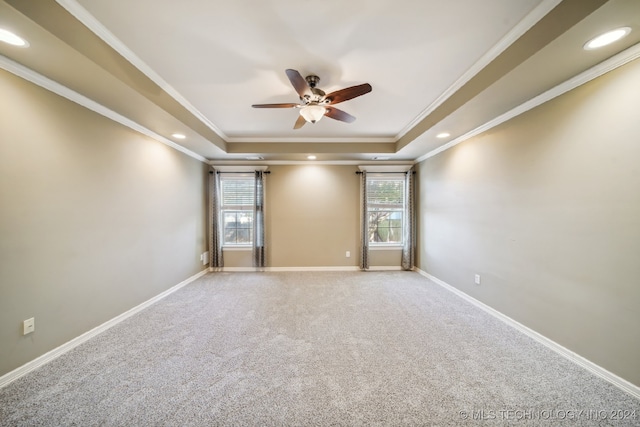 carpeted empty room featuring ceiling fan, crown molding, and a tray ceiling