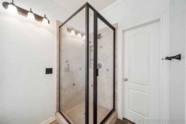 bathroom with a shower with door and crown molding