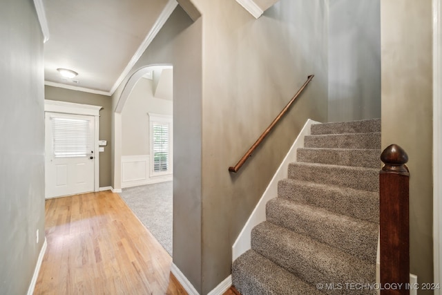 stairs with wood-type flooring and crown molding