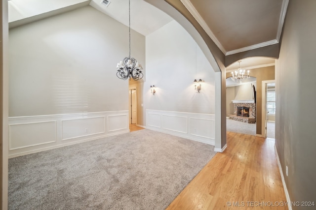 spare room with a fireplace, lofted ceiling, hardwood / wood-style floors, and crown molding