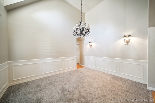 carpeted empty room featuring a chandelier and lofted ceiling