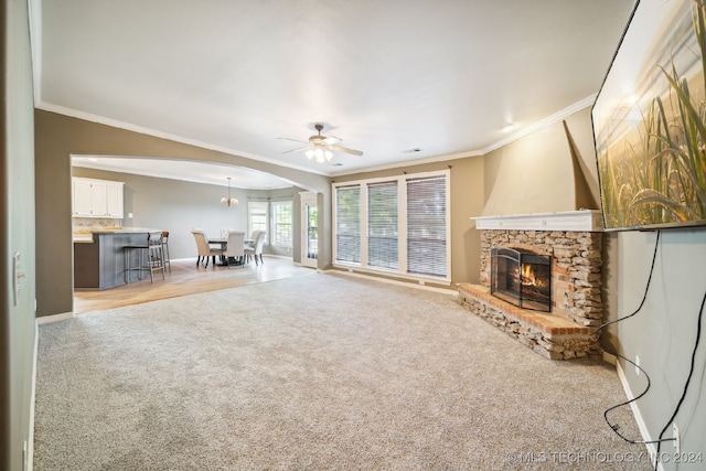 unfurnished living room with ornamental molding, light colored carpet, ceiling fan, and a stone fireplace