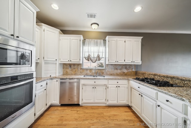 kitchen featuring light hardwood / wood-style floors, stainless steel appliances, sink, light stone countertops, and white cabinetry