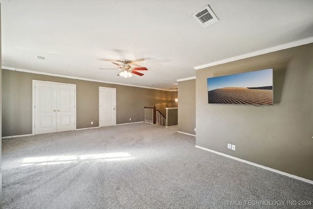 carpeted spare room with ceiling fan and crown molding