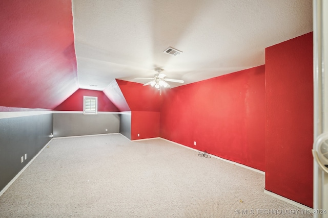 additional living space with a textured ceiling, vaulted ceiling, ceiling fan, and carpet floors