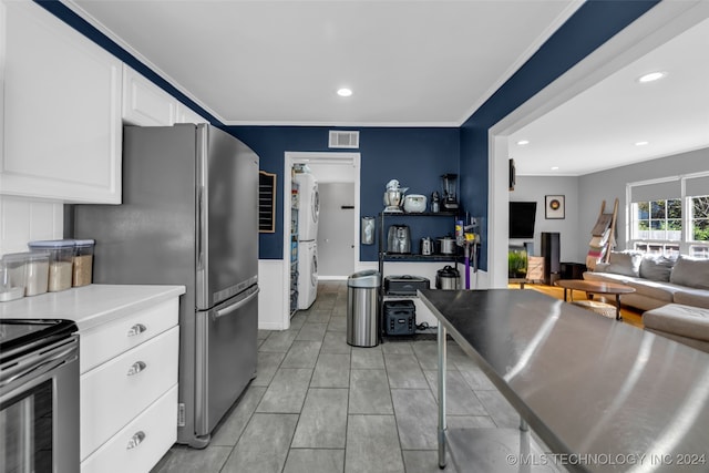 kitchen featuring stainless steel appliances, white cabinetry, stacked washer / drying machine, and ornamental molding