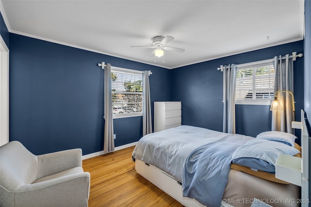 bedroom featuring hardwood / wood-style floors, ceiling fan, multiple windows, and ornamental molding