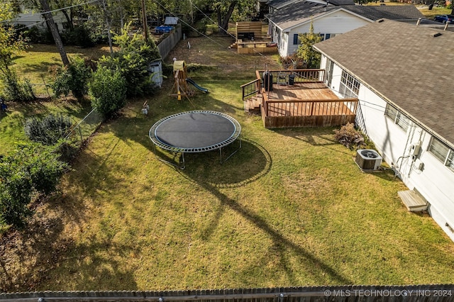 view of yard with central air condition unit, a playground, a trampoline, and a deck